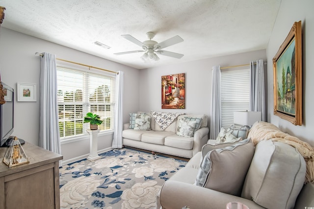 living room with a textured ceiling and ceiling fan