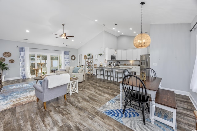 dining area with high vaulted ceiling, ceiling fan with notable chandelier, and hardwood / wood-style flooring