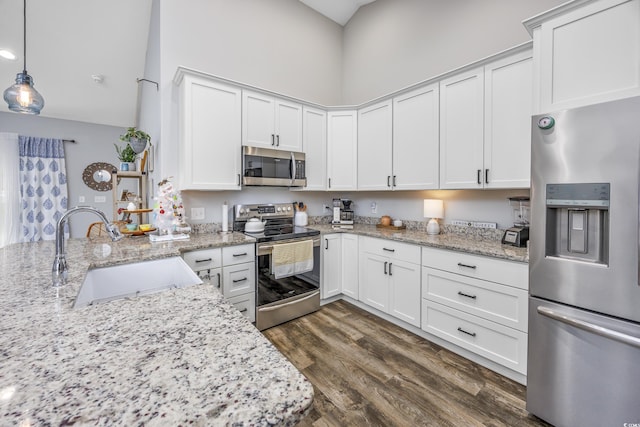 kitchen with light stone countertops, appliances with stainless steel finishes, sink, pendant lighting, and white cabinets