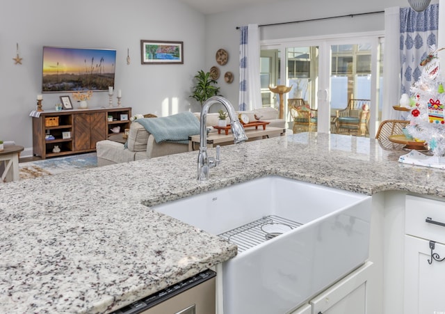 kitchen with light stone counters, sink, white cabinets, and lofted ceiling