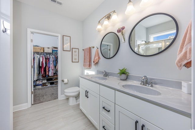 bathroom featuring vanity, a shower with shower door, and toilet