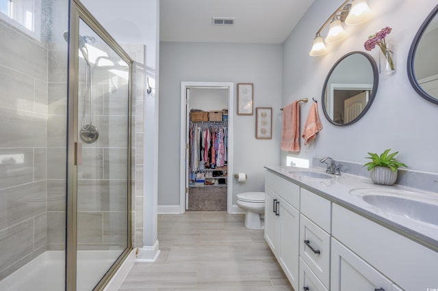 bathroom featuring tile patterned floors, vanity, a shower with shower door, and toilet