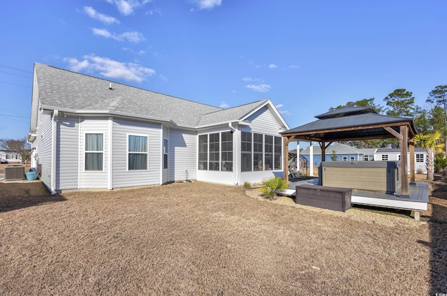 rear view of property with a gazebo, a sunroom, central air condition unit, and a hot tub