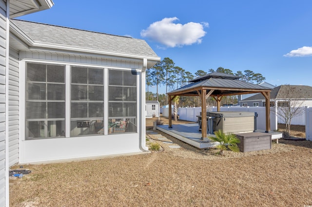 exterior space with a gazebo, a sunroom, a hot tub, and a deck