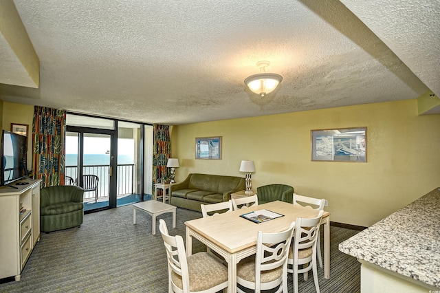 dining area featuring floor to ceiling windows, a water view, dark carpet, and a textured ceiling