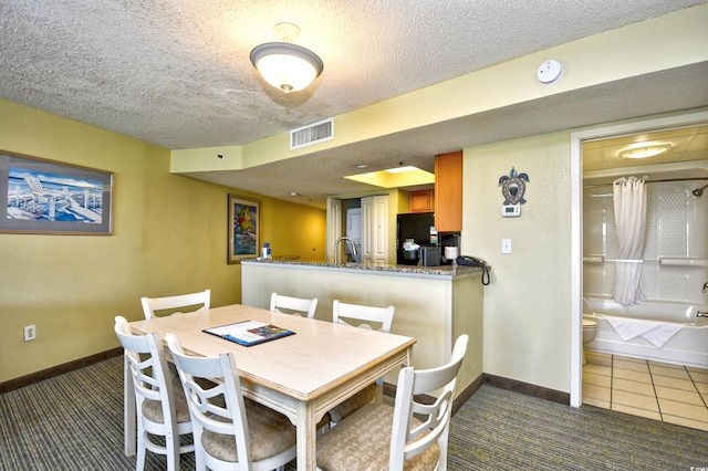 tiled dining area featuring sink and a textured ceiling