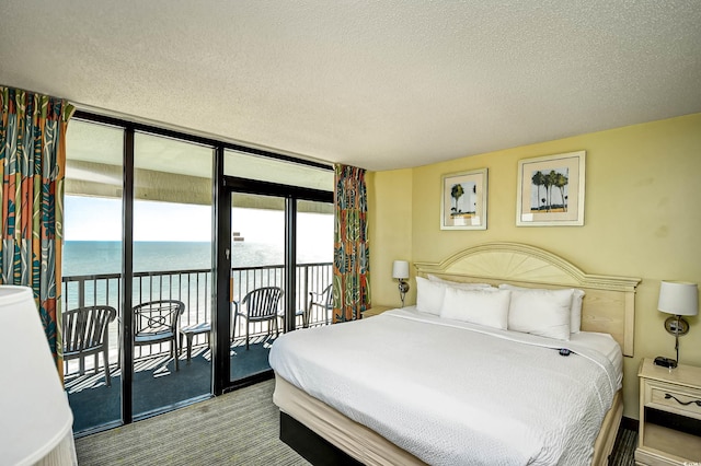 bedroom featuring a water view, a wall of windows, access to outside, and multiple windows