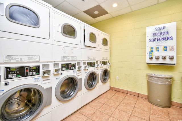 clothes washing area featuring stacked washer and dryer, light tile patterned floors, and washer and dryer