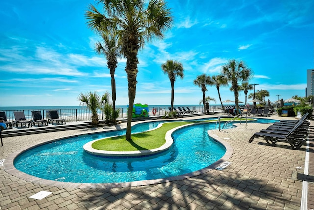 view of swimming pool featuring a water view and a patio area