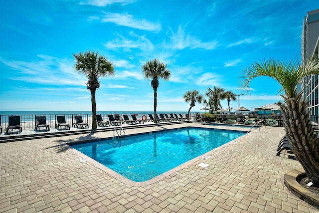 view of swimming pool with a patio area and a water view