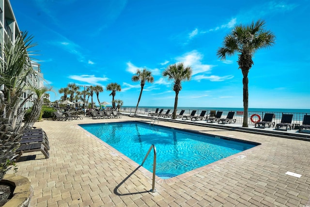 view of pool featuring a water view and a patio area