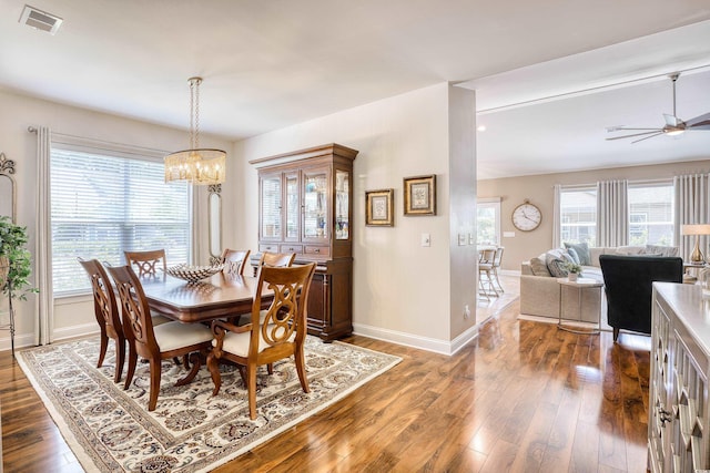 dining room with ceiling fan with notable chandelier, dark hardwood / wood-style flooring, and a wealth of natural light