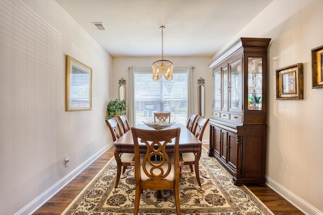 dining room with dark wood-type flooring and an inviting chandelier