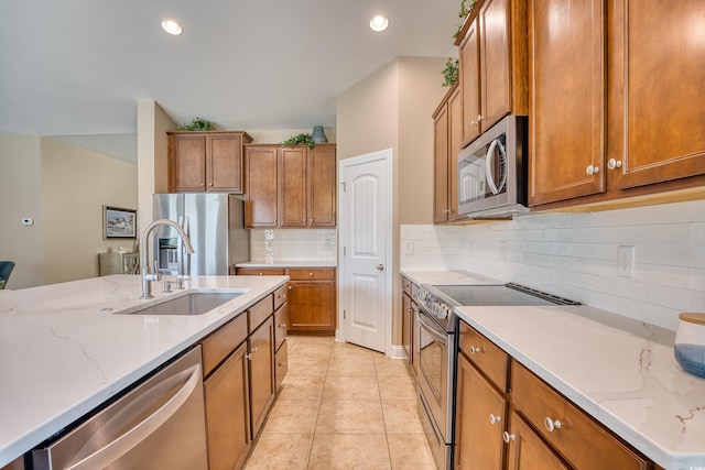 kitchen featuring sink, light stone countertops, tasteful backsplash, light tile patterned flooring, and stainless steel appliances