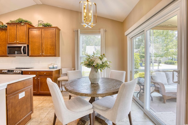 dining room with a chandelier, light tile patterned floors, and vaulted ceiling