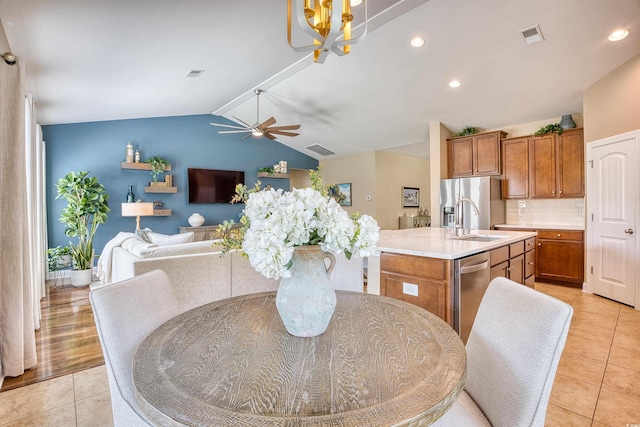 tiled dining area featuring ceiling fan with notable chandelier, lofted ceiling, and sink