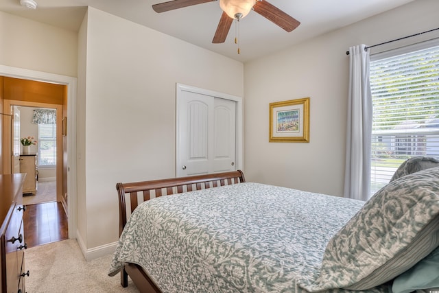 bedroom featuring ceiling fan, light colored carpet, and a closet