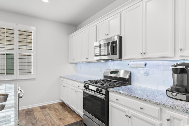 kitchen featuring tasteful backsplash, light stone counters, stainless steel appliances, white cabinets, and dark hardwood / wood-style floors