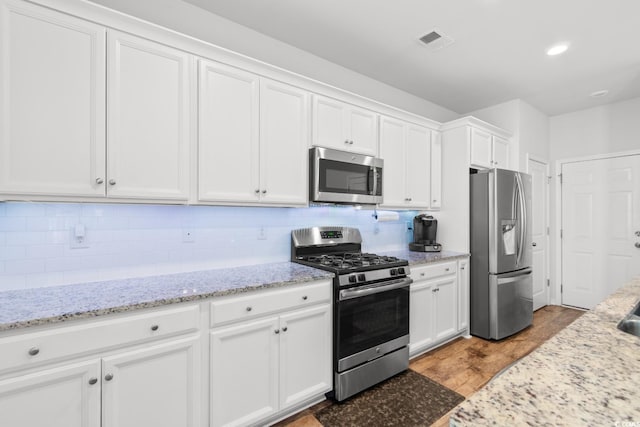 kitchen featuring white cabinets, decorative backsplash, hardwood / wood-style flooring, and appliances with stainless steel finishes