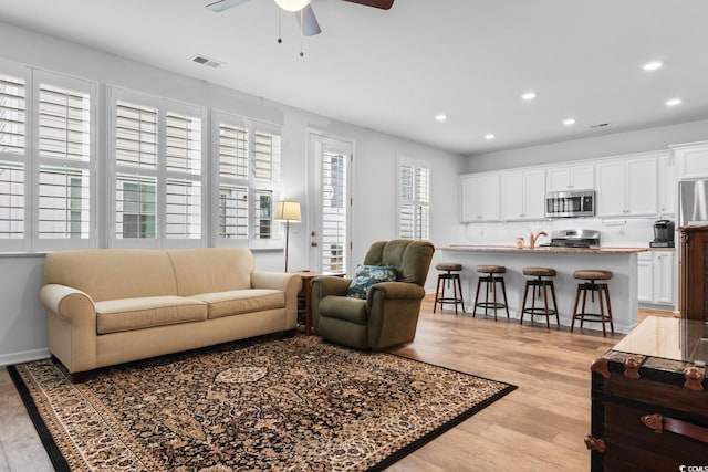 living room featuring plenty of natural light, ceiling fan, and light wood-type flooring