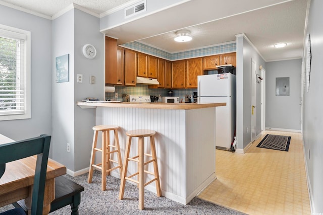 kitchen with a breakfast bar, white appliances, electric panel, decorative backsplash, and kitchen peninsula