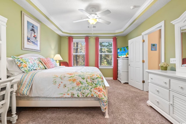 bedroom featuring ceiling fan, a raised ceiling, light colored carpet, a textured ceiling, and ornamental molding