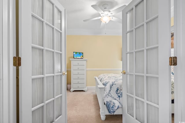 bedroom featuring ceiling fan, crown molding, light carpet, and french doors