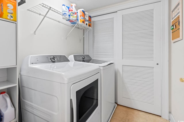 clothes washing area featuring washing machine and dryer and light tile patterned floors