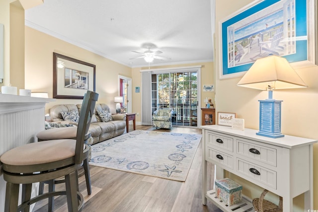 living room featuring crown molding, ceiling fan, and light wood-type flooring