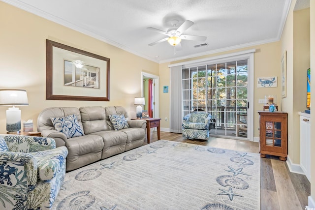 living room with a textured ceiling, light hardwood / wood-style floors, ceiling fan, and crown molding