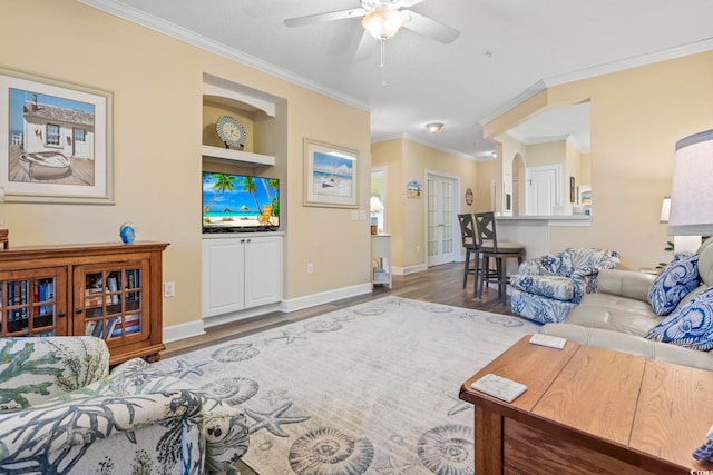 living room with hardwood / wood-style flooring, built in features, ceiling fan, and crown molding