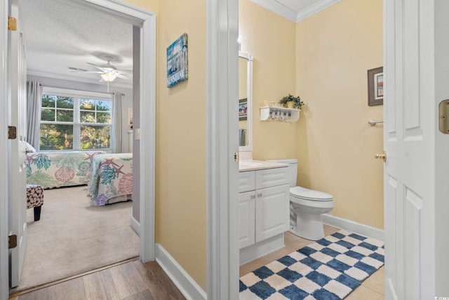 bathroom featuring ceiling fan, crown molding, wood-type flooring, a textured ceiling, and vanity