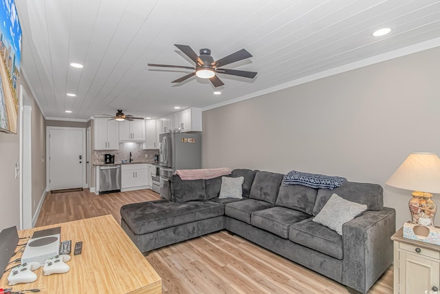 living room with ceiling fan, ornamental molding, sink, and light hardwood / wood-style flooring