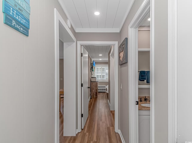 corridor featuring light wood-type flooring and ornamental molding