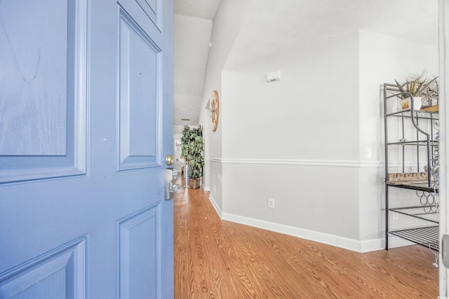 hall featuring a textured ceiling and light hardwood / wood-style floors