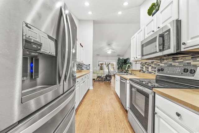 kitchen featuring decorative backsplash, appliances with stainless steel finishes, ceiling fan, light hardwood / wood-style flooring, and white cabinets