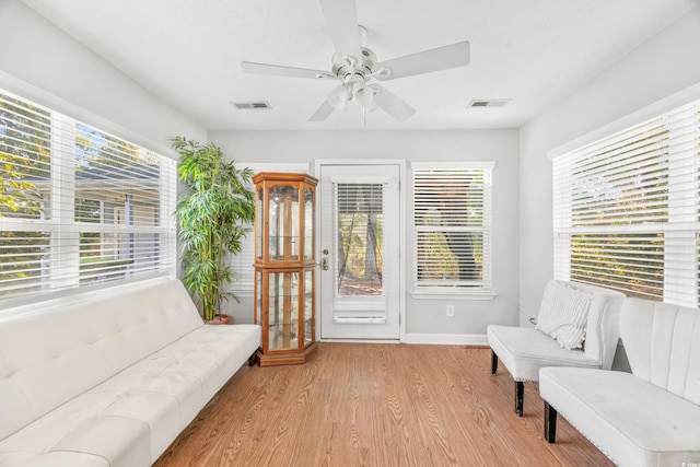 living area with ceiling fan, plenty of natural light, and light wood-type flooring