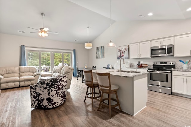 kitchen featuring stainless steel appliances, open floor plan, visible vents, and a sink