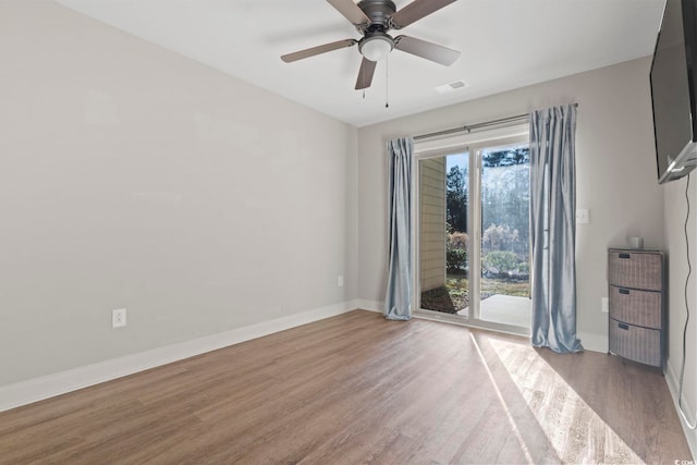 unfurnished room featuring a ceiling fan, visible vents, baseboards, and wood finished floors