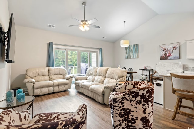 living room with lofted ceiling, light wood-type flooring, visible vents, and a ceiling fan