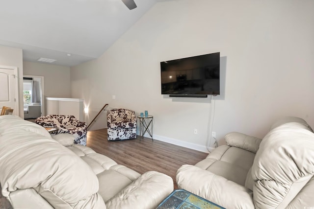 living room featuring lofted ceiling, visible vents, baseboards, and wood finished floors