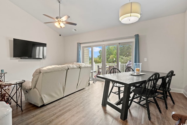 dining room with light wood finished floors, visible vents, a ceiling fan, vaulted ceiling, and baseboards