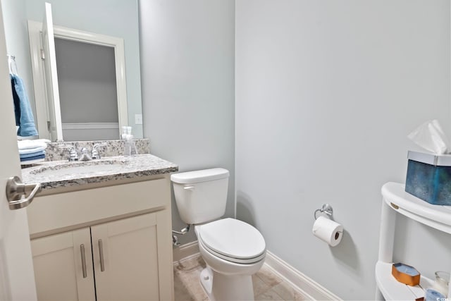 half bath featuring vanity, toilet, and baseboards