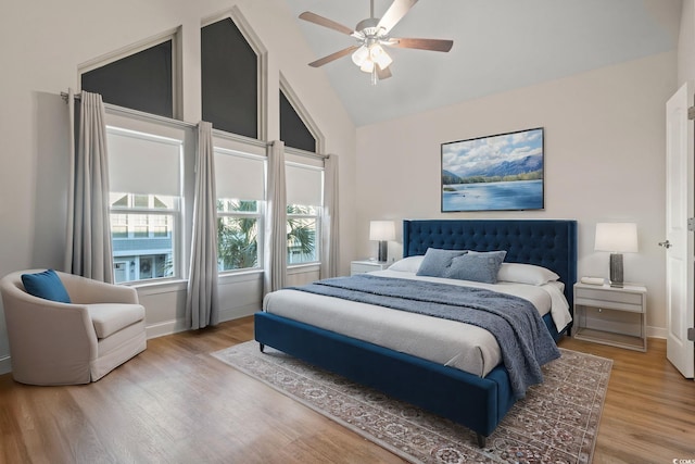 bedroom with high vaulted ceiling, ceiling fan, baseboards, and wood finished floors