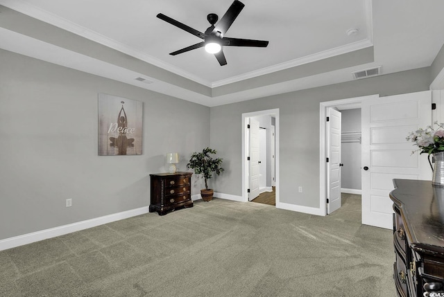 interior space featuring a tray ceiling, ceiling fan, crown molding, connected bathroom, and a closet