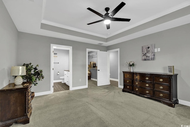 bedroom with a spacious closet, ceiling fan, ensuite bathroom, a tray ceiling, and a closet