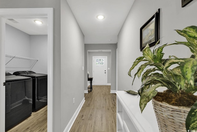 hallway with separate washer and dryer and light hardwood / wood-style floors