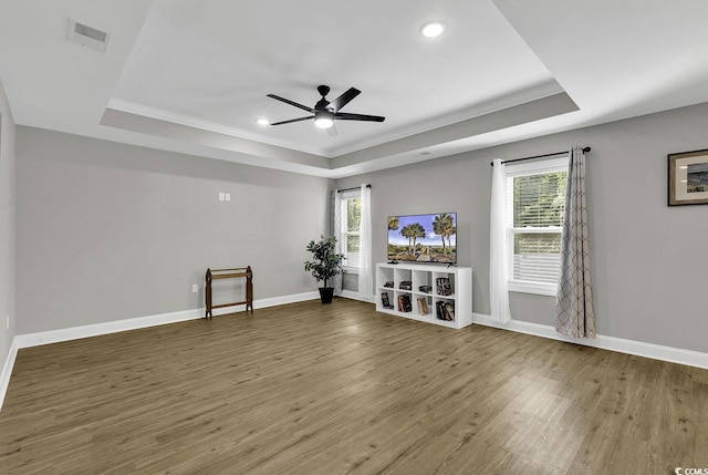 unfurnished living room featuring a raised ceiling and plenty of natural light