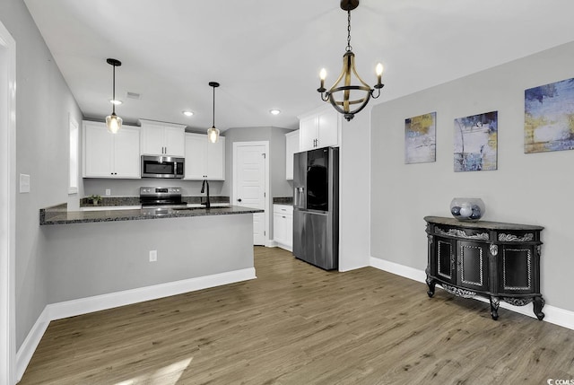 kitchen featuring a chandelier, pendant lighting, white cabinets, and stainless steel appliances