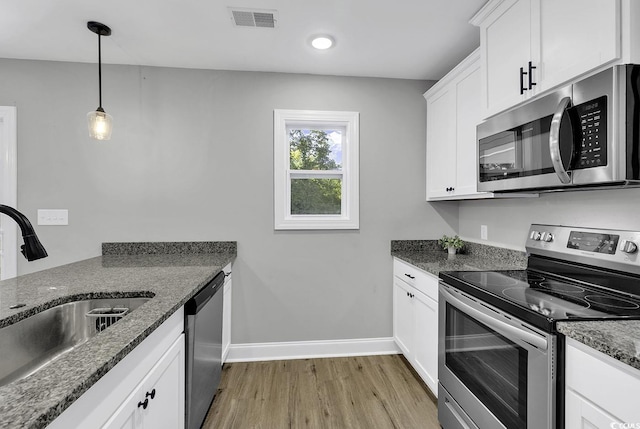 kitchen with dark stone counters, sink, white cabinets, and stainless steel appliances